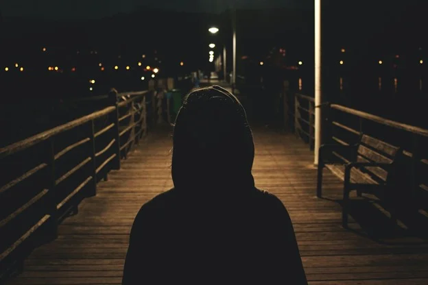 A person stands on a dimly lit pier at night, symbolising hope in the search for missing individuals